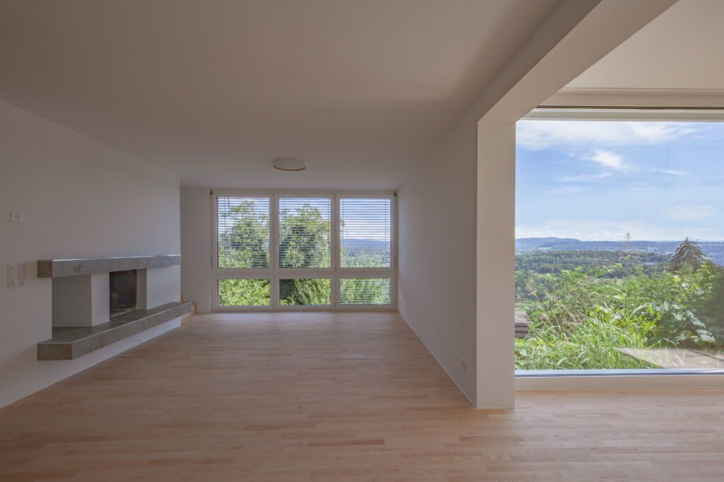 Wohnraum mit zwei grossen Fenstern mit Blick ins Grüne