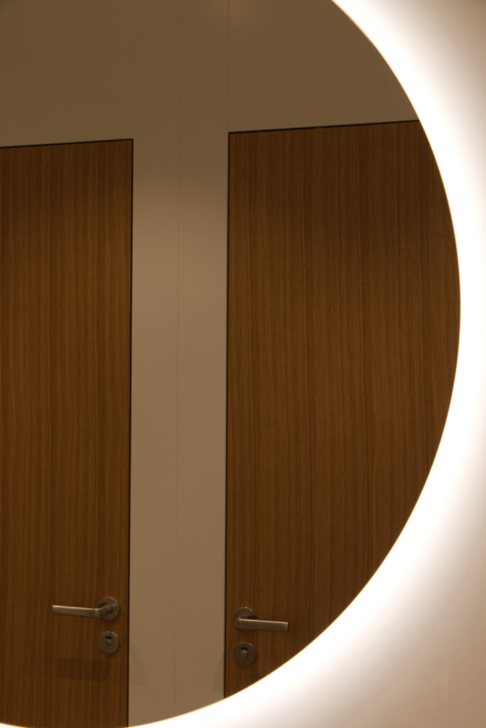 zwei Türen spiegeln sich in einem runden Spiegel mit Hinterleuchtung